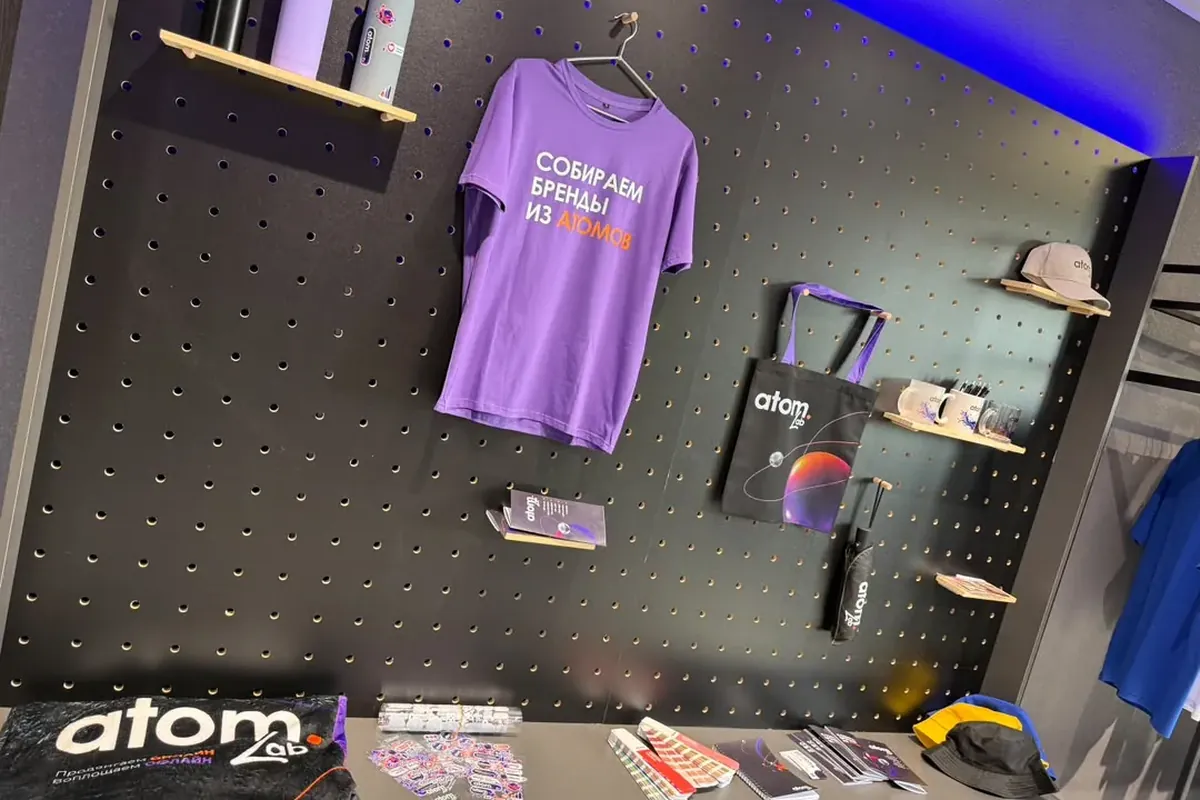Стена с корпоративным мерчем в шоуруме ATOM LAB: футболка, шоппер, кепка, зонт, блокноты