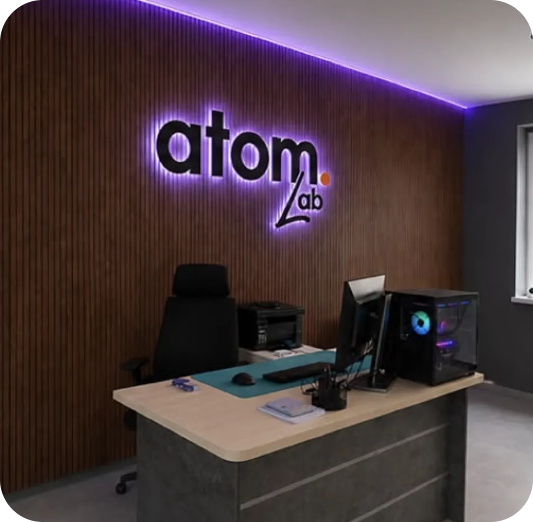 Шоурум ATOM LAB: стойка ресепшн и светящийся логотип atom lab на стене